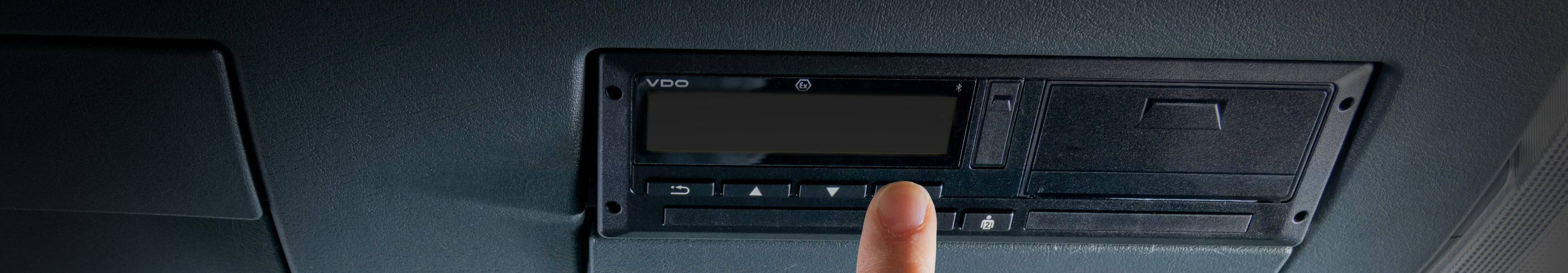 A hand is about to press a button on the new VDO DTCO 4.1 and turn the device on.